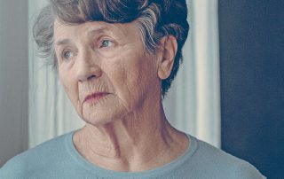 Senhora olhando para o nada, simbolizando alguém com Doença de Alzheimer