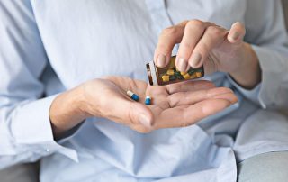 Homem colocando pílulas em sua mão para tomar como automedicação