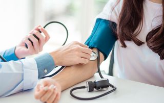 Médico aferindo pressão sanguínea de paciente para ver se ela tem pressão alta